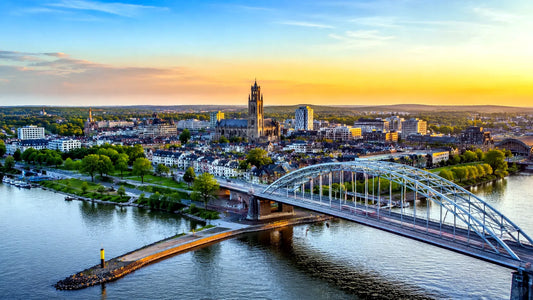 panoramafoto van de iconische John Frostbrug over de Rijn in Arnhem, Nederland, met uitzicht op de historische binnenstad bij zonsondergang – professionele landmarkfoto voor meubels herstofferen en meubelstoffering in Arnhem