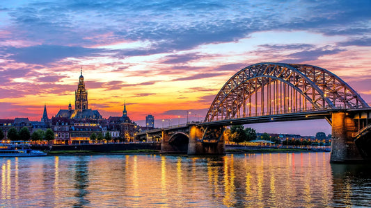Breedbeeldfoto van de iconische Waalbrug en historische skyline van Nijmegen, Nederland, met uitzicht over de rivier bij zonsondergang – professionele 8K landmarkfoto voor meubels herstofferen en meubelstoffering in Nijmegen