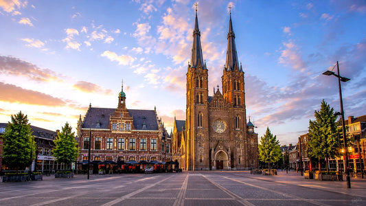Breedbeeldfoto van de Heuvelse Kerk en het historische stadsplein in Tilburg, Nederland, bij zonsondergang – hoogwaardige 8K landmarkfoto voor meubels herstofferen en meubelstoffering in Tilburg