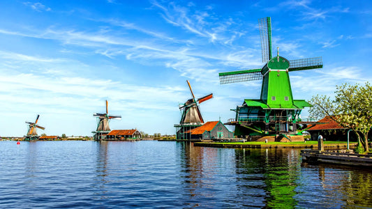 Breedbeeldfoto van de iconische Zaanse Schans met traditionele groene windmolens aan het water in Zaanstad, Nederland – sfeervolle 8K landmarkfoto voor meubels herstofferen en meubelstoffering in Zaanstad
